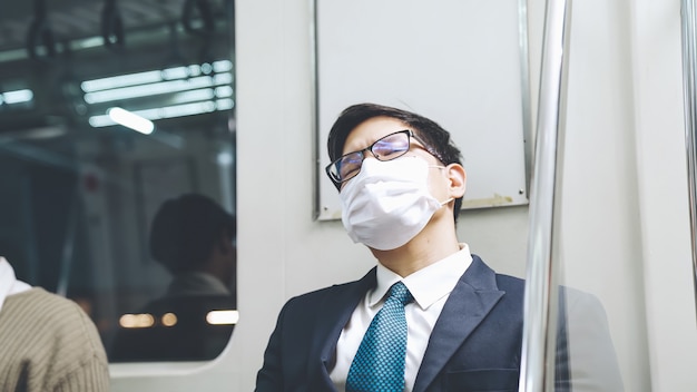 Un jeune homme portant un masque facial voyage dans une rame de métro bondée