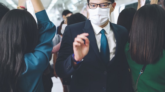 Un jeune homme portant un masque facial voyage dans une rame de métro bondée