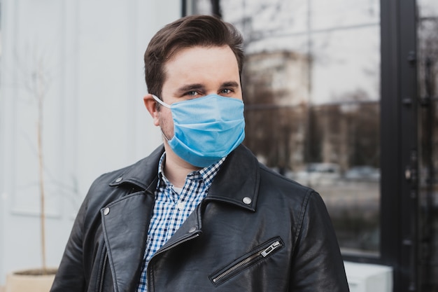 Jeune homme portant un masque sur un fond de café fermé, coronavirus, maladie, infection, quarantaine, masque médical