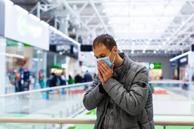 Un jeune homme portant un masque médical dans un centre commercial. L'homme masqué se protège de l'épidémie du virus chinois "2019-nKoV"