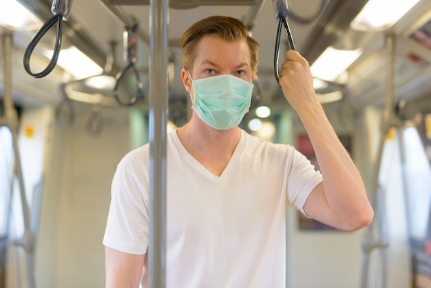 Jeune homme portant un masque de protection contre l'épidémie de virus corona à l'intérieur du train