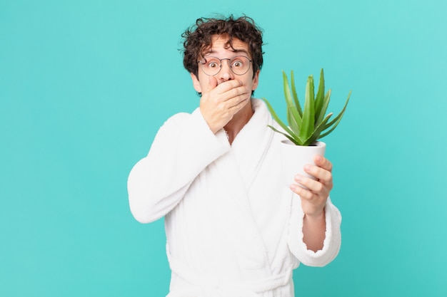 jeune homme portant un peignoir couvrant la bouche avec les mains avec un choc