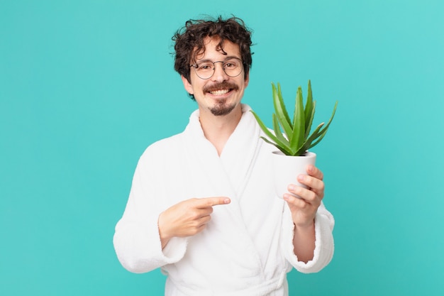 Jeune homme portant un peignoir souriant joyeusement, se sentant heureux et pointant vers le côté