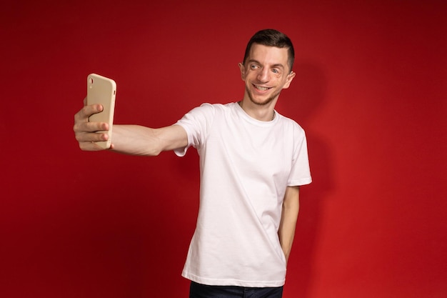 Un jeune homme portant un t-shirt blanc atteint du syndrome de Treacher prend des selfies sur son téléphone personnes handicapées maladie génétique