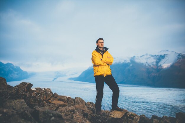 Jeune homme portant une veste d'hiver jaune debout au glacier Vatnajokull