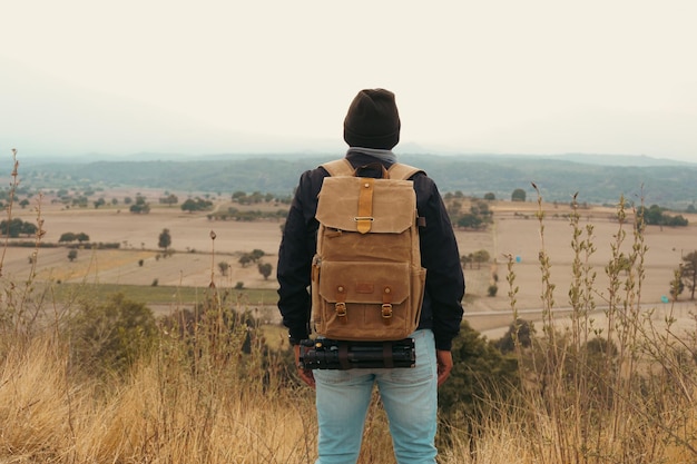 Jeune homme portant une veste et un sac à dos lors d'un trek en plein air dans les montagnes