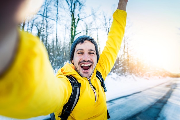 Jeune homme portant des vêtements d'hiver prenant une photo de selfie dans la forêt de neige d'hiver