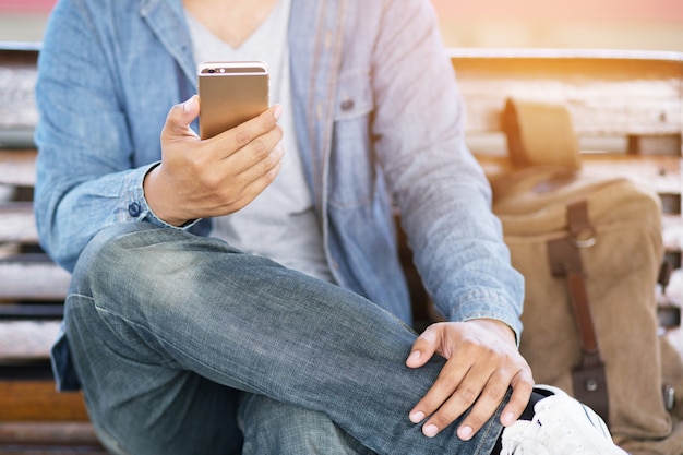 Jeune homme porte une chemise à carreaux. gros plan à l'aide de téléphone portable pendant le repos sur le canapé. assis à regarder