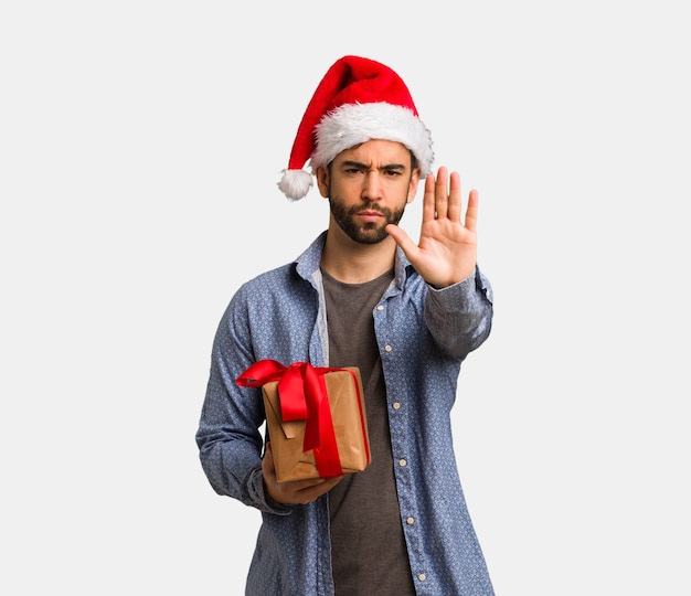 Jeune homme, porter, noël chapeau, mettre, main devant