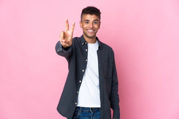 Jeune homme posant isolé contre le mur blanc