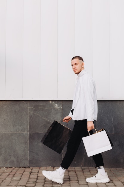 Jeune homme posant avec des sacs à provisions le vendredi noir