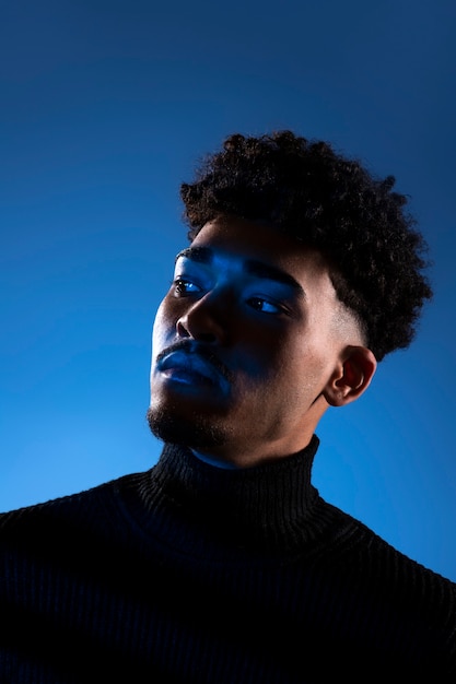 Jeune homme posant avec vue latérale sur fond bleu