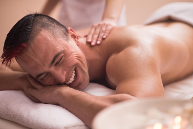 Jeune homme positif ayant un massage du dos dans un centre de spa