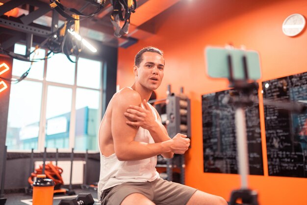 Jeune homme positif touchant ses gros biceps