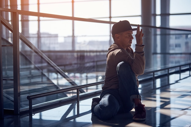 Jeune homme pratique le yoga asana à l'intérieur dans le hall vide de l'aéroport