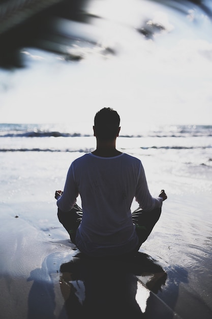 Jeune Homme Pratique Le Yoga Sur La Plage Au Coucher Du Soleil.