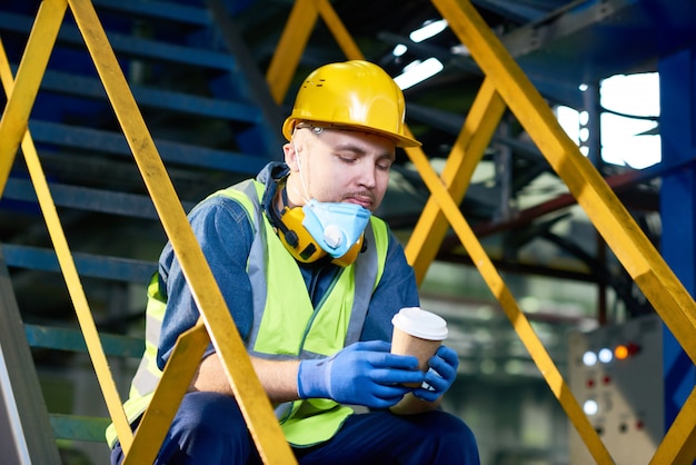 Jeune homme prenant une pause-café à l'usine