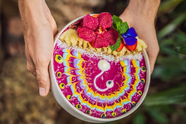 Un jeune homme prenant un petit-déjeuner méditerranéen mange un bol de smoothie de petit-déjeuner tropical sain avec