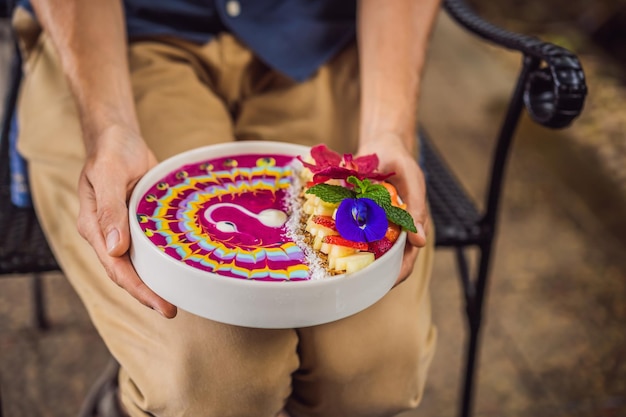 Un jeune homme prenant un petit déjeuner méditerranéen mange un bon petit-déjeuner tropical avec un smoothie