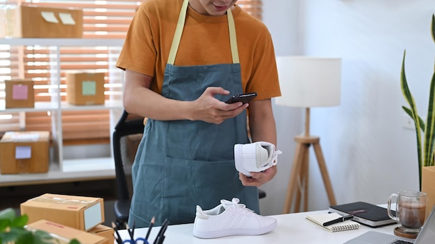 Jeune homme prenant une photo de produit avec un smartphone numérique pour poster à vendre en ligne sur internet