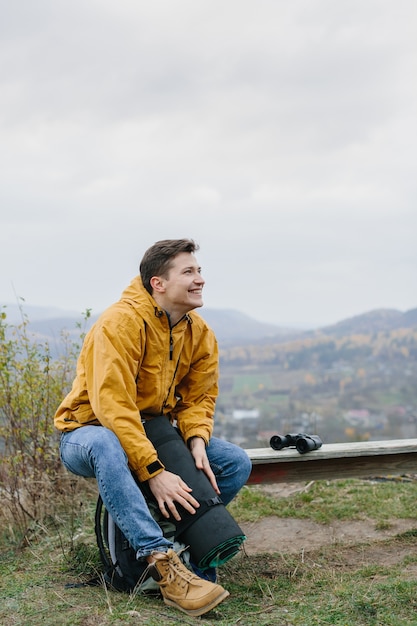 Jeune homme prépare l'équipement assis sur un banc dans un terrain montagneux