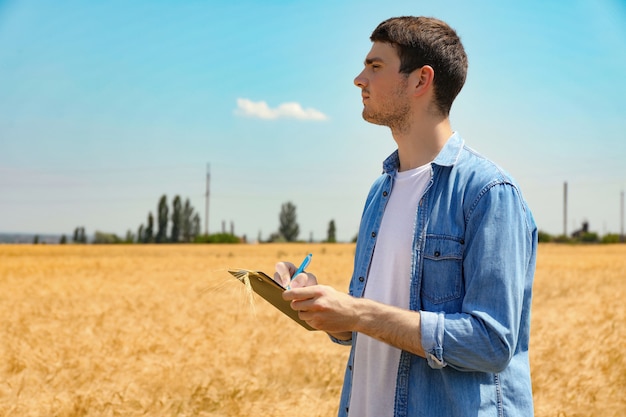 Jeune homme avec presse-papiers dans le champ d'orge