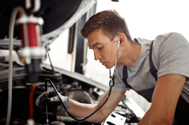 Un jeune homme procède à un examen détaillé d'un moteur de voiture dans un atelier automobile