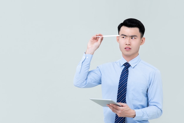 Jeune homme professionnel asiatique réfléchie tenant le stylet à la tête à côté de l'espace de copie