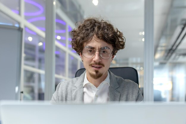 Un jeune homme professionnel aux cheveux bouclés absorbé par le travail à son bureau incarnant l'entreprise