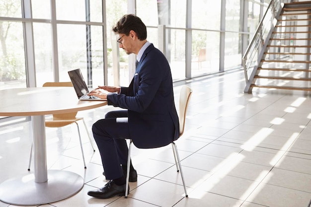 Jeune homme professionnel utilisant un ordinateur portable sur toute la longueur