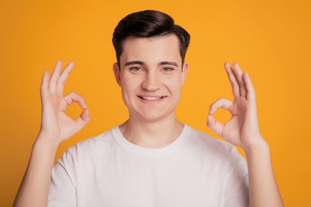 Jeune homme promoteur sur fond jaune isolé montre signe ok avec deux mains