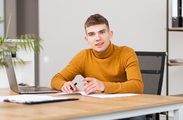 Jeune homme prospère travaillant avec des documents au bureau