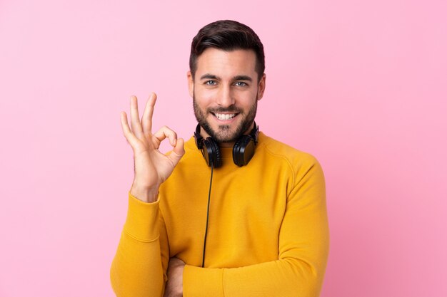 Jeune homme avec un pull jaune faisant un geste ok