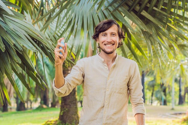 Jeune homme pulvérisant un insectifuge contre les moustiques dans la protection contre les insectes de la forêt