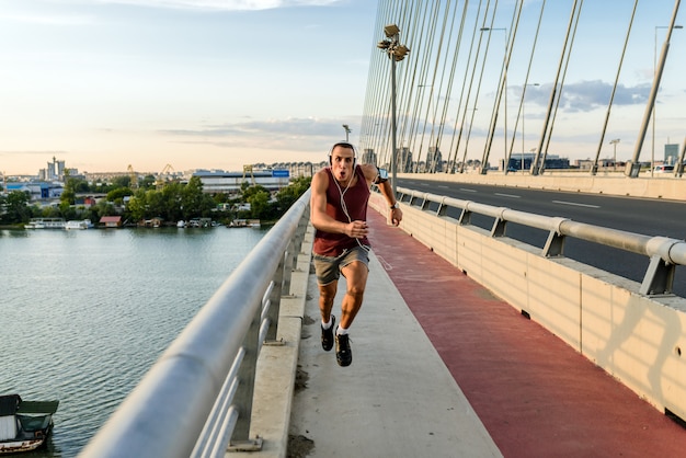 Jeune homme qui court sur le pont moderne de la ville