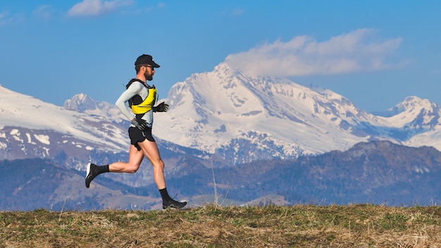 Jeune homme qui court sur une prairie de montagne