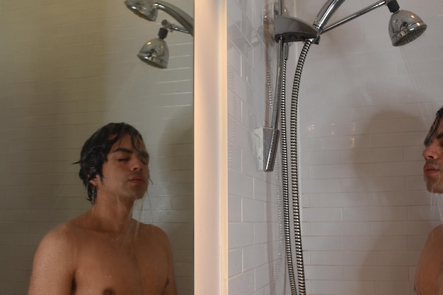 Un jeune homme qui regarde sous la douche.