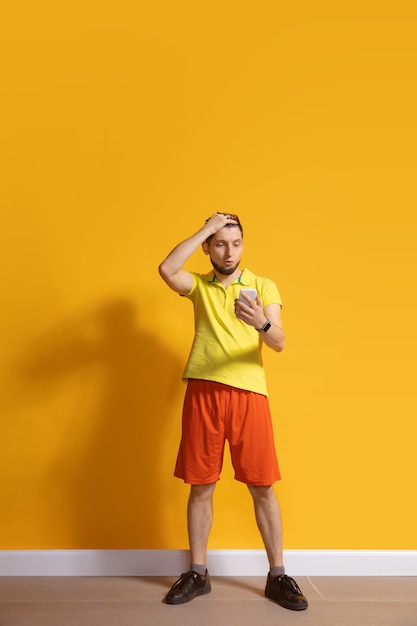 Jeune homme de race blanche à l'aide de smartphone portrait de pleine longueur du corps isolé sur mur jaune