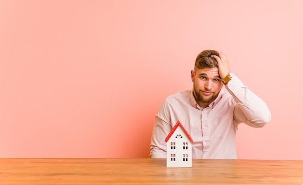 Jeune homme de race blanche assise avec une icône de la maison étant choquée, elle s'est souvenue d'une réunion importante.