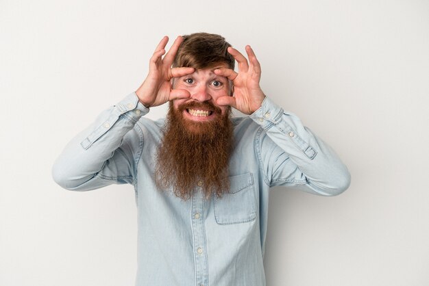 Jeune homme de race blanche au gingembre avec une longue barbe isolé sur fond blanc en gardant les yeux ouverts pour trouver une opportunité de succès.