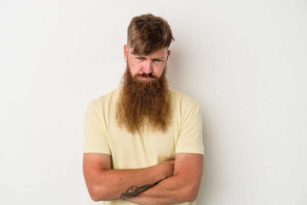 Jeune homme de race blanche au gingembre avec une longue barbe isolé sur fond blanc malheureux à la recherche à huis clos avec une expression sarcastique.