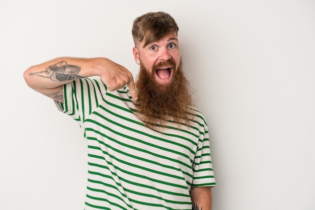 Jeune homme de race blanche au gingembre avec une longue barbe isolé sur fond blanc personne pointant à la main vers un espace de copie de chemise, fier et confiant