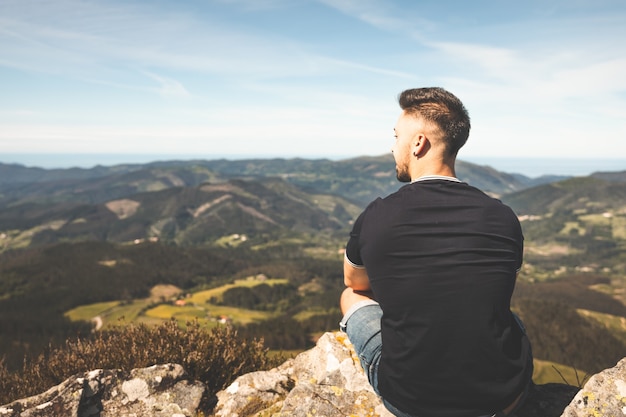 Jeune homme de race blanche au sommet de la montagne Oiz avec une vue imprenable sur tout le pays basque verdoyant.