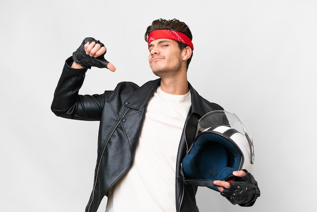 Jeune homme de race blanche avec un casque de moto sur fond blanc isolé fier et satisfait