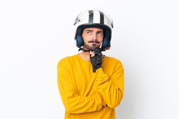 Jeune homme de race blanche avec un casque de moto isolé sur fond blanc ayant des doutes et pensant