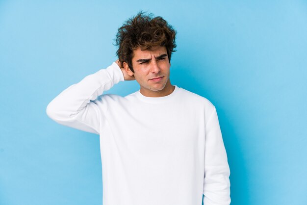 Jeune homme de race blanche contre un mur bleu isolé souffrant de douleurs au cou en raison du mode de vie sédentaire.