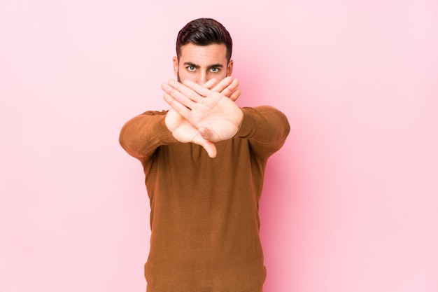 Jeune homme de race blanche contre un mur rose isolé faisant un geste de déni