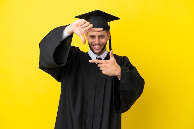 Jeune homme de race blanche diplômé universitaire isolé sur fond jaune se concentrant sur le visage. Symbole d'encadrement
