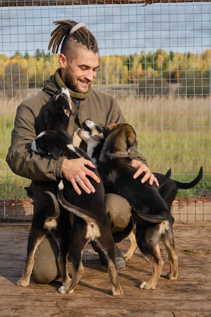 Un jeune homme de race blanche avec des dreadlocks choisit un chiot du refuge chenil Alaskan Husky