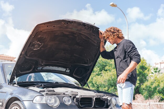 Jeune homme de race blanche essayant de réparer une panne dans sa voiture